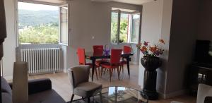 a living room with a dining room table and red chairs at Villa Mas Fa Susa 3 étoiles avec piscine in Les Vans