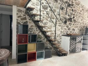 uma escada com prateleiras coloridas ao lado de uma parede de pedra em maison de caractère em Peyroules
