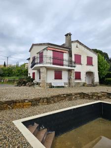 uma casa com portas vermelhas e uma piscina em frente em Villa Mas Fa Susa 3 étoiles avec piscine em Les Vans