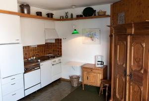 a small kitchen with white cabinets and a sink at Wunderbarer Panoramablick in Les Collons