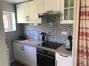 a kitchen with white cabinets and a black sink at Jolie maison de compagne in Suilly-la-Tour