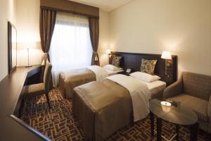 千葉市にあるオークラ千葉ホテルのベッド2台とソファが備わるホテルルームです。