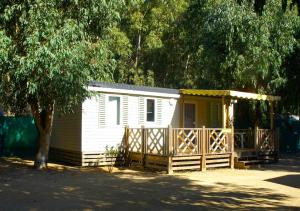 une petite maison blanche avec une véranda et un arbre dans l'établissement Camping Dolce Vita, à Calvi