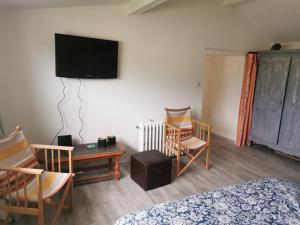 Habitación con cama, sillas y TV. en Bouvet Vincent, en Saint-Cyr-en-Val