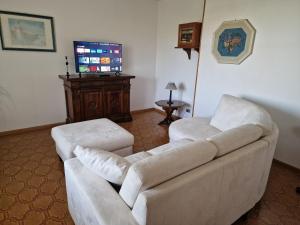 Habitat - Casa Vacanze Perugia في بيروجيا: غرفة معيشة بها كنبتين بيضاء وتلفزيون