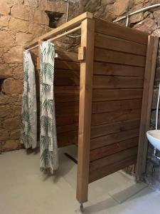 une cabine de douche en bois devant un mur en pierre dans l'établissement Au village, à Serriera