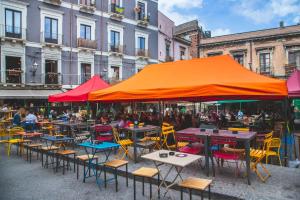 un grupo de mesas y sillas bajo una sombrilla naranja en 4Roomsrelax, en Catania