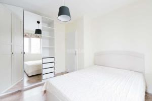 ein weißes Schlafzimmer mit einem Bett und einem Spiegel in der Unterkunft Apartment in Boyana in Sofia