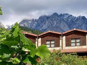 une maison en bois avec des montagnes en arrière-plan dans l'établissement Picos de Europa Suites and Rooms, à Turieno