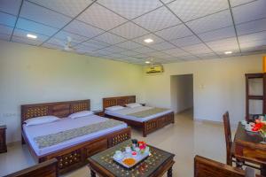 2 camas en una habitación con mesas y sillas en Jawai Dam Stay, en Bīsalpur