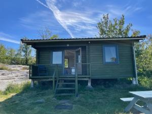 a green tiny house with a porch and a picnic table at Klobbars Gästhem o Stugor in Kökar