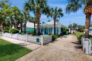 a house with palm trees and a white picket fence at Cotton Candy in Destin