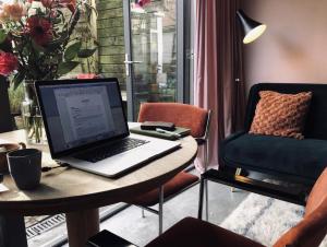 a laptop computer sitting on a table next to a chair at Deborah's Hiding Place in Alkmaar