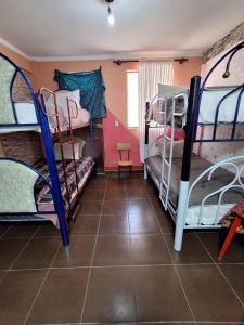 a room with three bunk beds and a tile floor at Backpacker Oruro in Oruro