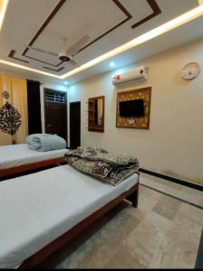 - une chambre avec 2 lits et une télévision murale dans l'établissement IVY Guest House II, à Islamabad