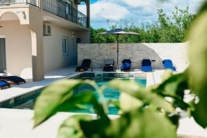 une maison dotée d'une piscine avec des chaises et un parasol dans l'établissement Villa Marta, à Mala Čista
