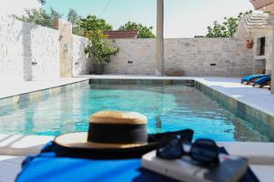 un chapeau et des lunettes de soleil assis dans une piscine dans l'établissement Villa Marta, à Mala Čista