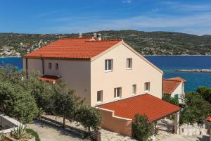 a white house with a red roof next to the water at maris sevid in Zaglavice