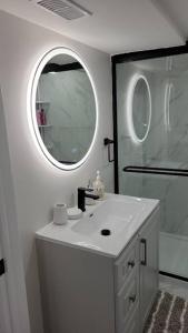 Baño blanco con lavabo y espejo en Cheerful 1 Bedroom Apartment with kitchennete en Ajax