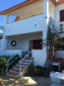 une maison blanche avec des escaliers et une horloge. dans l'établissement Casa Indipendente Praialonga, à Le Castella