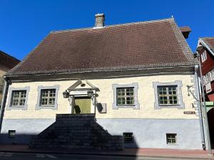 a white house with a yellow door on a street at Kivivete Apartaments in Pärnu