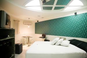 Vert Motel Parnamirim في بارناميريم: غرفة نوم بسرير ابيض بجدار اخضر
