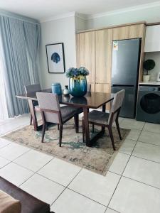 a dining room table with chairs and a blue vase on it at Napo Luxury stay in Pretoria +1 photo