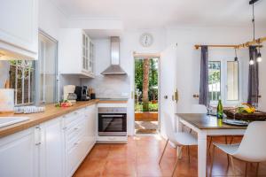 une cuisine avec des placards blancs et une table avec des chaises dans l'établissement Villa Pedro strandnah ruhig zentral, à Can Pastilla