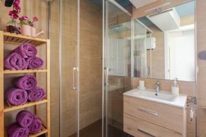 y baño con ducha de cristal y toallas púrpuras. en VutSanClemente Exclusivo a 100 metros de la Catedral en Santiago de Compostela