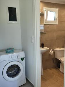 ein Badezimmer mit einer Waschmaschine und einem Waschbecken in der Unterkunft Tarmaros Apartments in Sisi