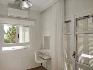 a white bathroom with a window and a white chair at Tarmaros Apartments in Sissi