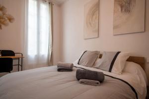 ein Schlafzimmer mit einem großen weißen Bett mit Handtüchern darauf in der Unterkunft Un Cocon Au Cœur d'Avignon Logement in Avignon