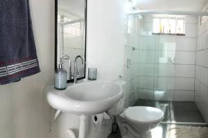 La salle de bains blanche est pourvue d'un lavabo et de toilettes. dans l'établissement Pé na Areia em Ilha de Maré, à Salvador