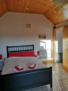 Sunriseview Cottages في ويكلو: غرفة نوم بها سرير ووسادتين حمرا