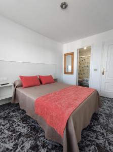 a bedroom with a large bed with red pillows at Apartamentos Faxilda in Sanxenxo
