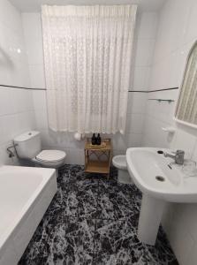 a white bathroom with a sink and a toilet and a tub at Apartamentos Faxilde in Sanxenxo