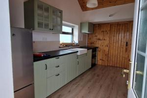 uma cozinha com armários brancos e um balcão preto em Sunriseview Cottages em Wicklow