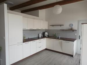 a white kitchen with white cabinets and a wooden floor at Apartment Odrlice in Senice na Hané