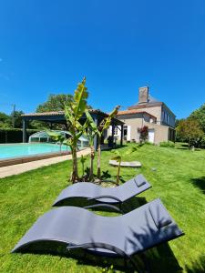 einen Garten mit zwei Stühlen und einem Baum neben einem Haus in der Unterkunft Chambre d'hôte BALI in La Roche-sur-Yon