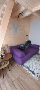 Borostyánkút Wellness Home Bakonybél في باكونيبل: غرفة معيشة مع أريكة أرجوانية وطاولة