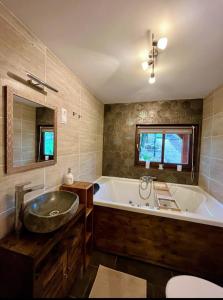 ein Badezimmer mit einer großen Badewanne und einem Waschbecken in der Unterkunft Borostyánkút Wellness Home Bakonybél in Bakonybél