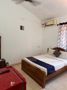 1 dormitorio con 1 cama y 1 maleta roja en Sun and Sea, Calangute en Goa