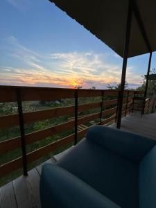 a view of the sunset from a deck with a couch at Căsuța de pe deal in Hlincea