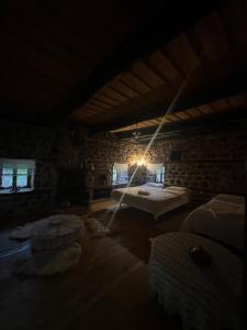 Habitación oscura con 2 camas y pared de piedra. en Kulla Hupi Agriturism, en Bulqizë