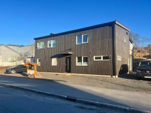 Un gran edificio marrón con un coche aparcado delante. en Kabelvåg city apartment, en Kabelvåg