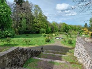 een tuin met een stenen muur en een brug bij Chambres d'hotes au Domaine des Possibles in Orcines