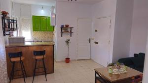 una cocina con armarios verdes y 2 taburetes en Bensassi Urban Escape, en La Marsa