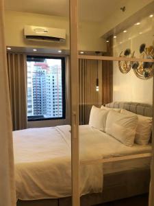 - une chambre avec un grand lit blanc et une fenêtre dans l'établissement Urbanview Oasis at Air Residences, à Manille