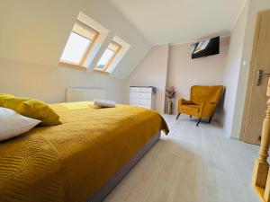 1 dormitorio con cama amarilla y silla amarilla en Górska Przystań SPA, en Krynica-Zdrój