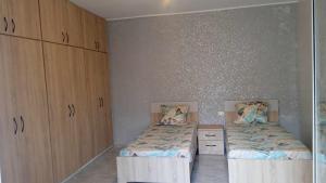 1 dormitorio con 2 camas individuales y armarios de madera en Room Breakfast, en Zarzouna